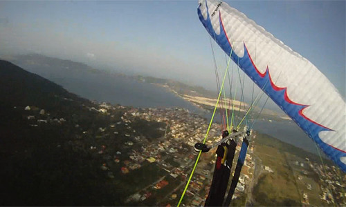 Parapente branco durante um SAT abordo com lagoa ao fundo