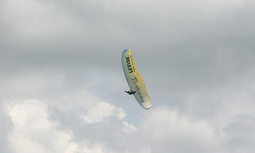 Parapente amarelo durante um SAT com nuvens ao fundo